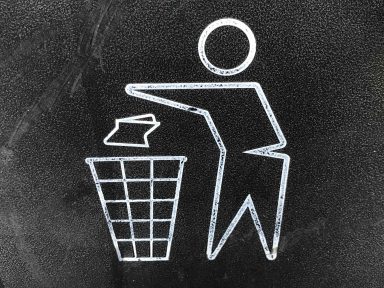 Symbol einer Person, die Papier in einen Mülleimer wirft.